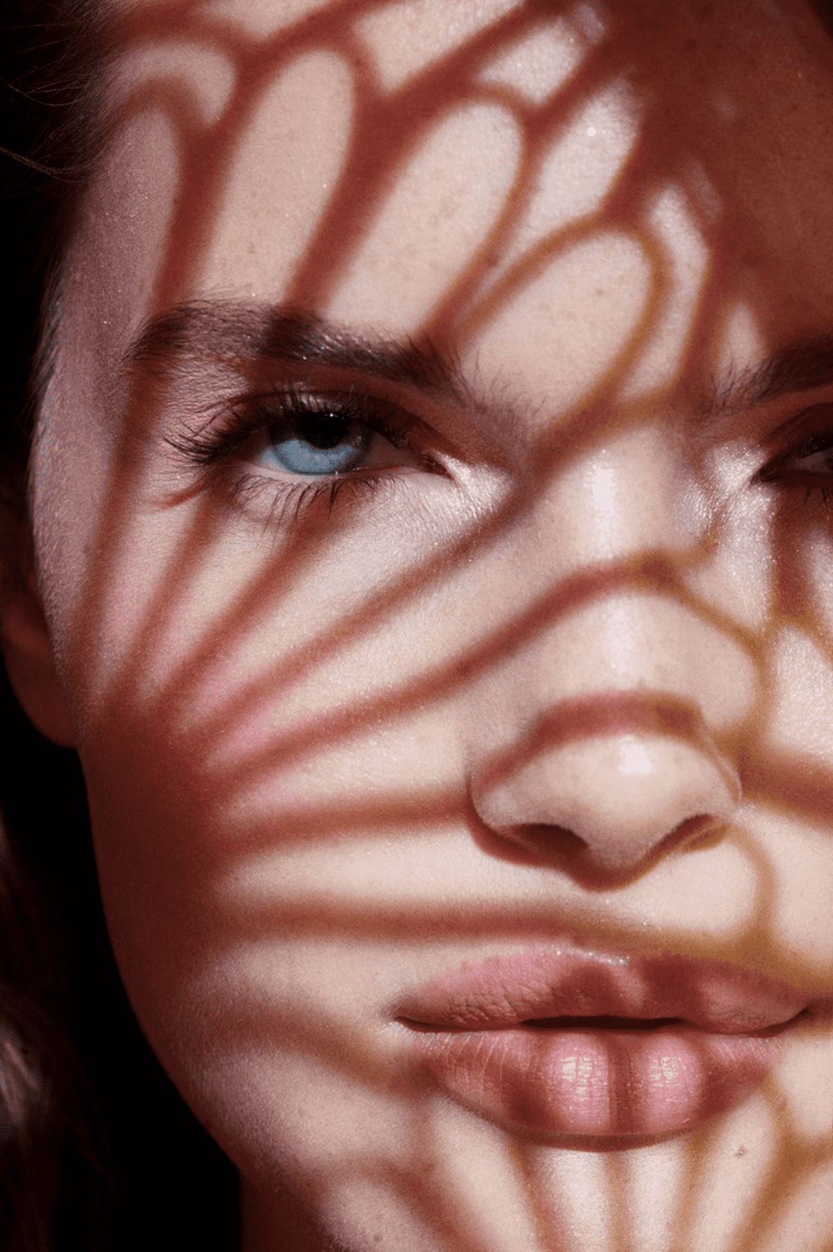 Close up of models face with a shadow cut out one side of her face